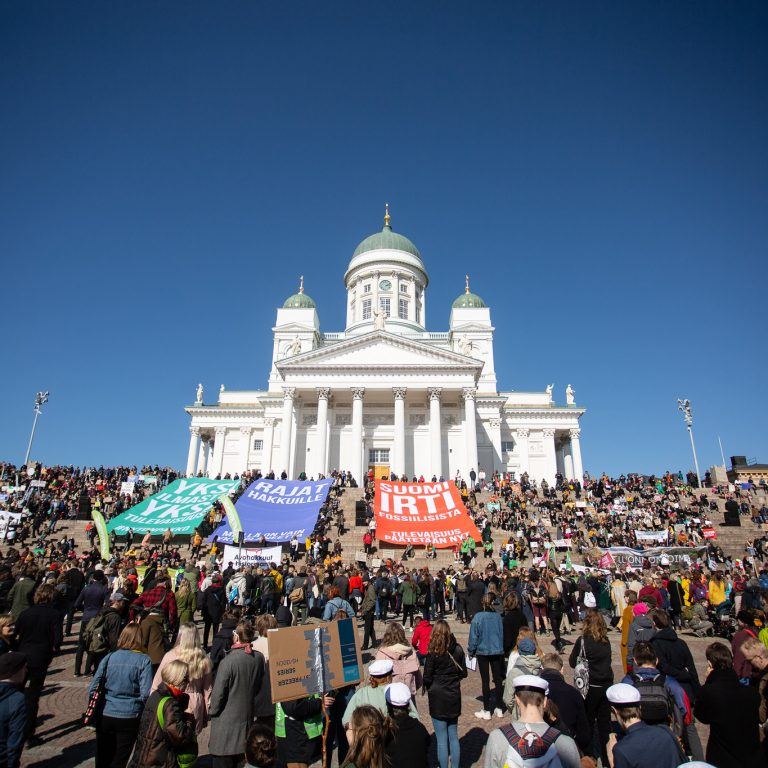 Photo from climate march in Helsinki. A large group of people and a big white church in the picture.