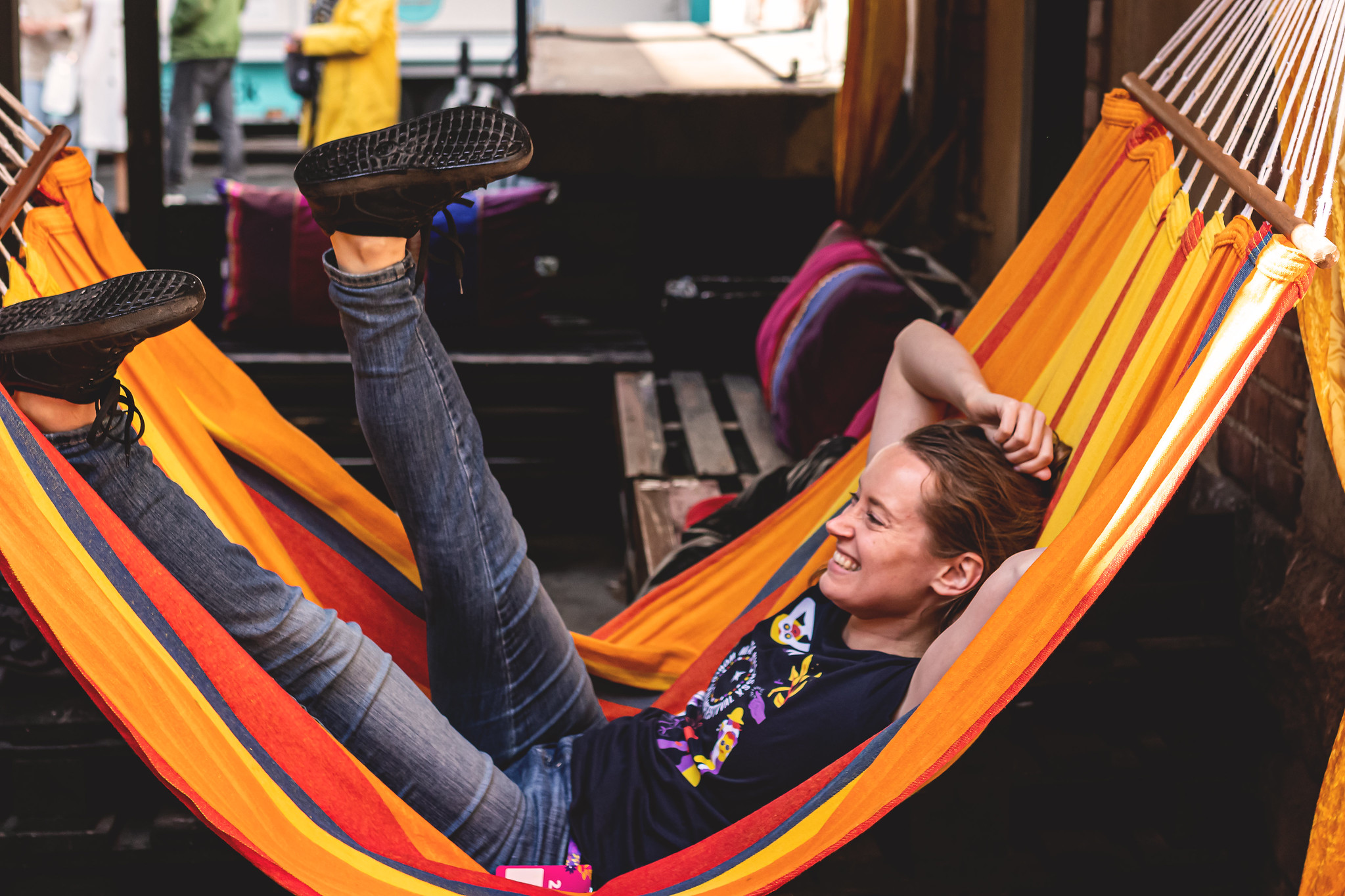 A person wearing a festival t-shirt happily lounging on a hammock.