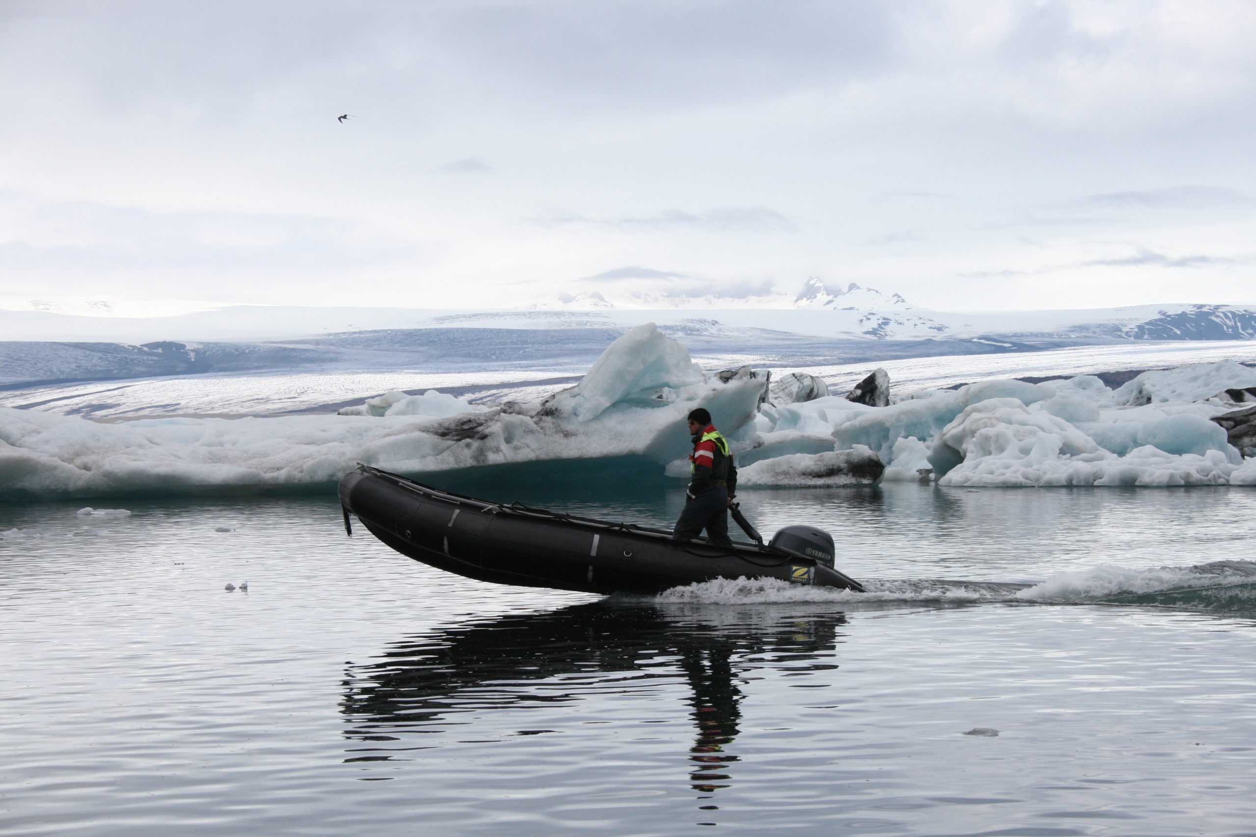 Kuvassa mies ajaa kumiveneellä sulavan jäätikön jäätikköjärvessä