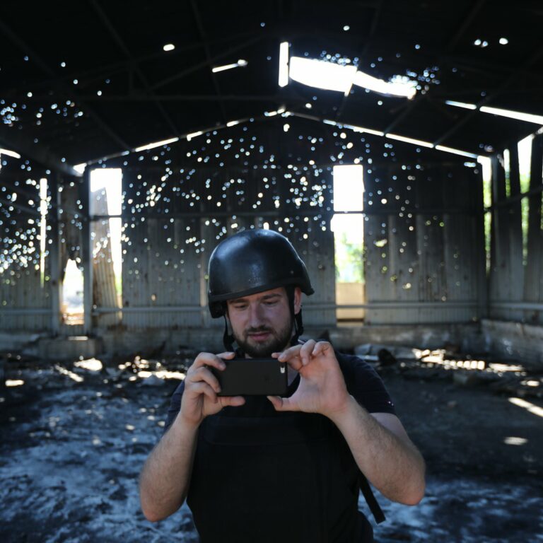 Illia Ponomarenko ottaa valokuvaa kännykällä sodassa tuhoutuneen rakennuksen sisällä.