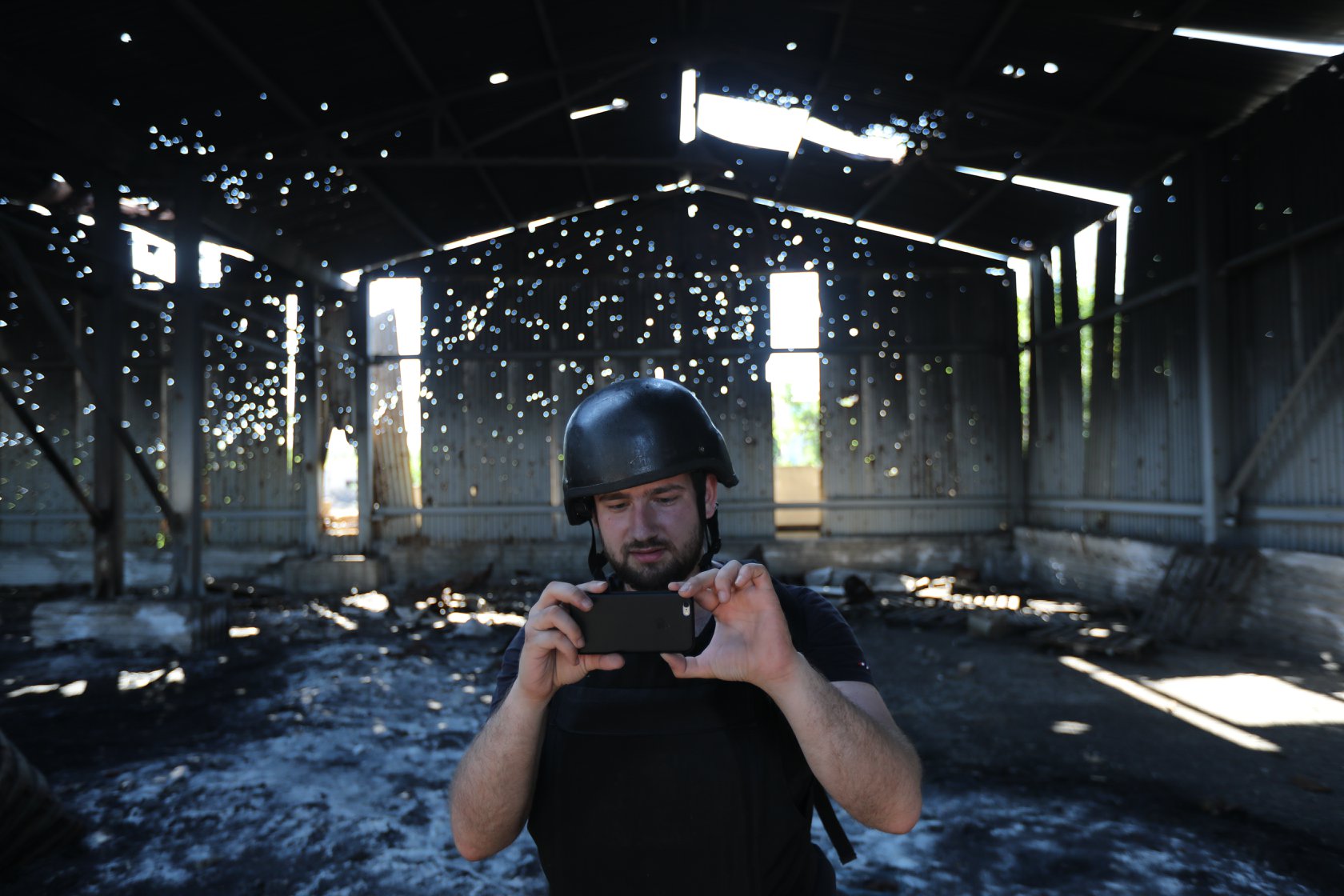 Illia Ponomarenko ottaa valokuvaa kännykällä sodassa tuhoutuneen rakennuksen sisällä.