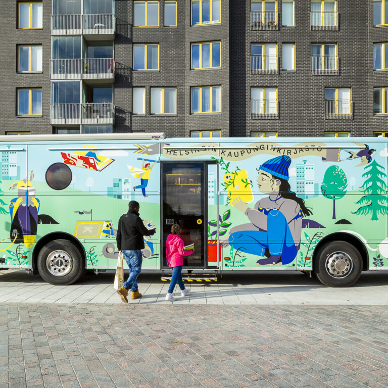 A colorful bus and people in front of apartment buildings.