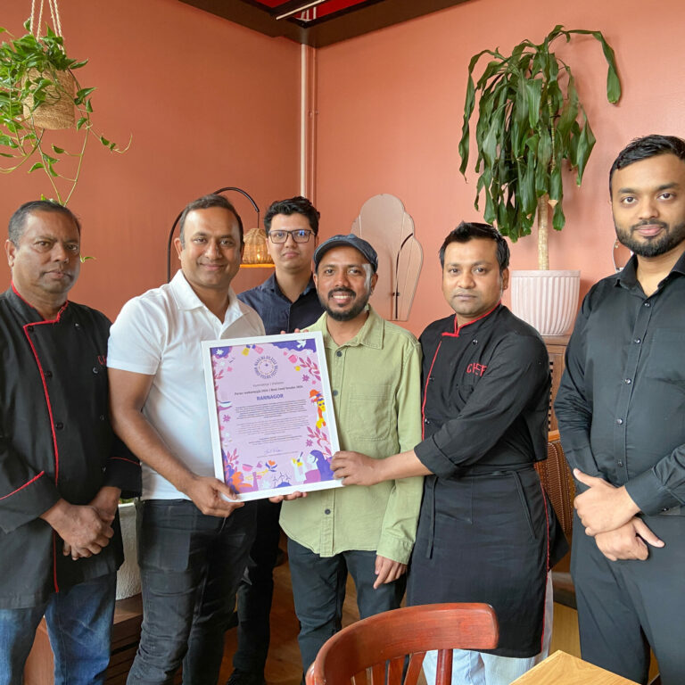 In a group photo, the restaurant's staff with a framed diploma.