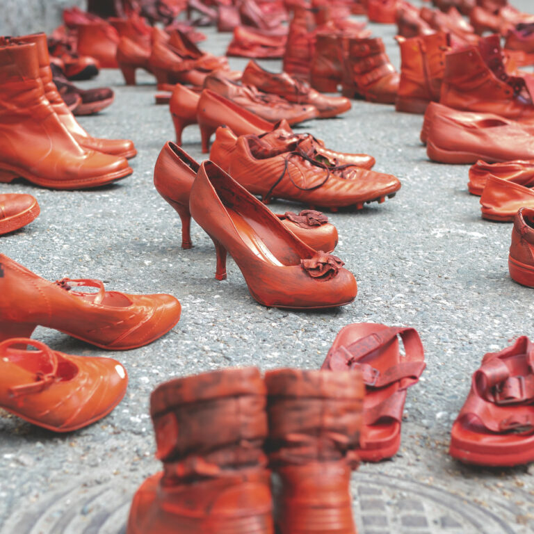 Red painted shoes on asphalt.